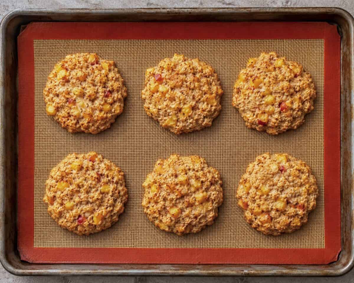 Fresh baked peach breakfast cookies on silat lined baking sheet.