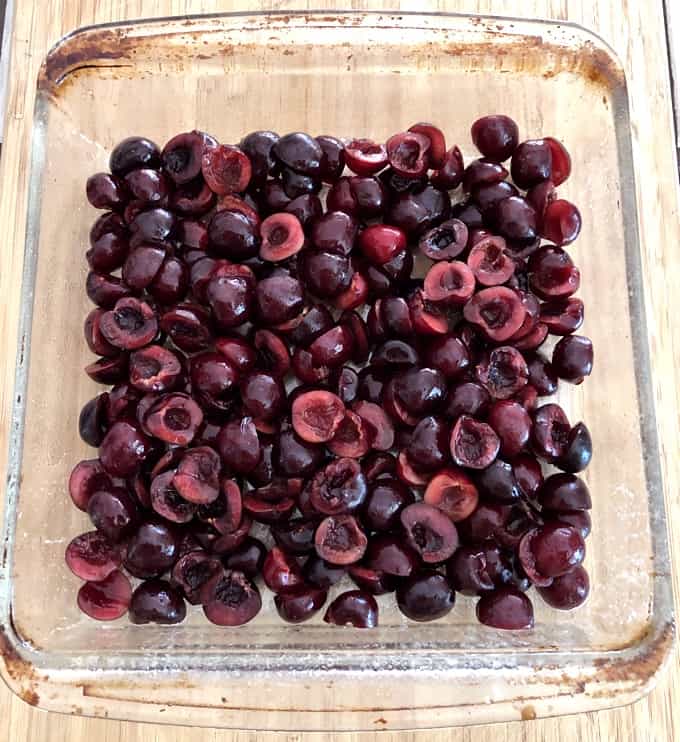 Pitted fresh cherries in glass baking dish.
