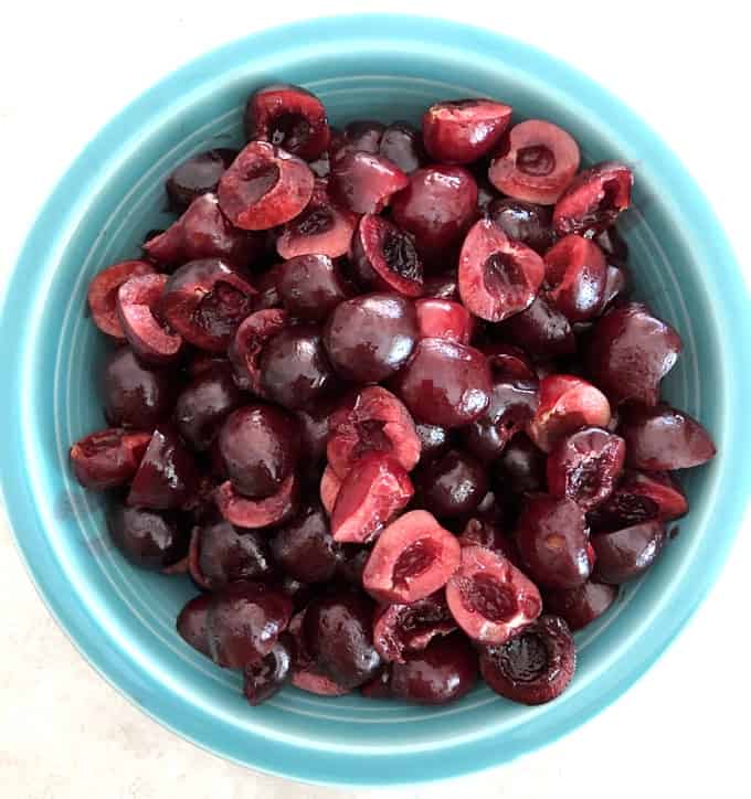Pitted fresh cherries in green bowl.