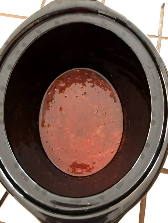Black crock pot with Sriracha hot sauce and honey mixture.