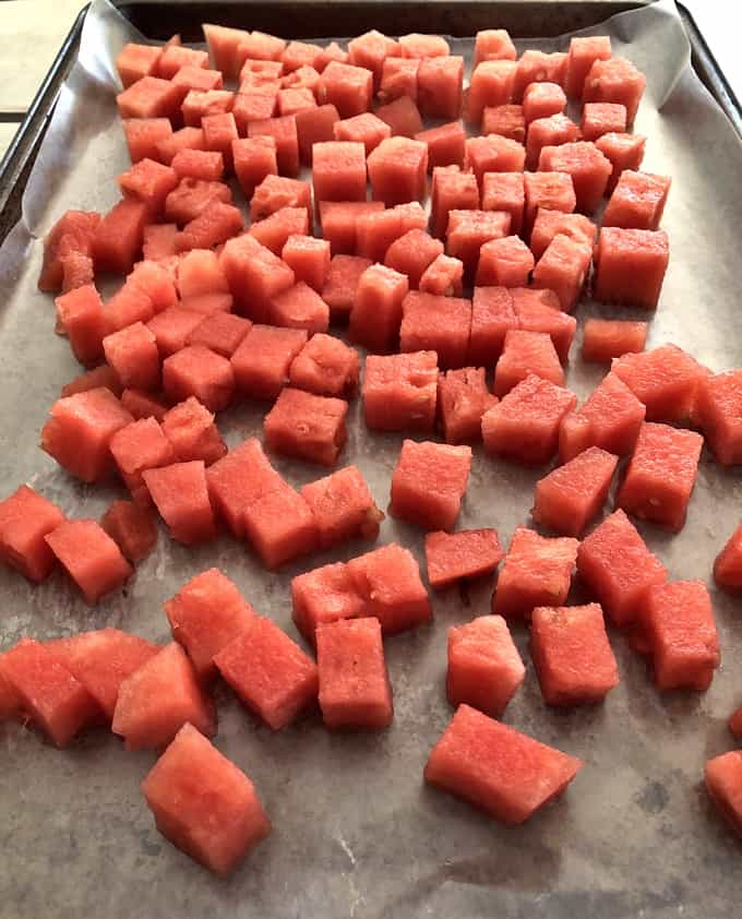 Cubed watermelon on parchment paper lined baking sheet.