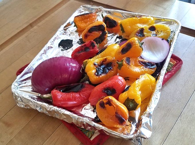 Red onions and roasted mini sweet peppers on foil-line tray.