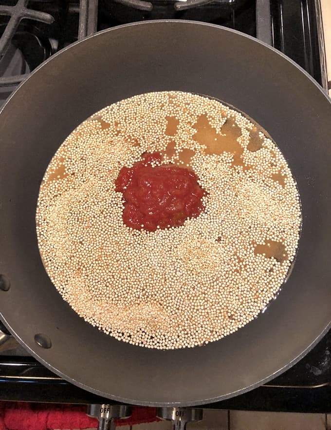 Cooking quinoa with salsa in skillet.