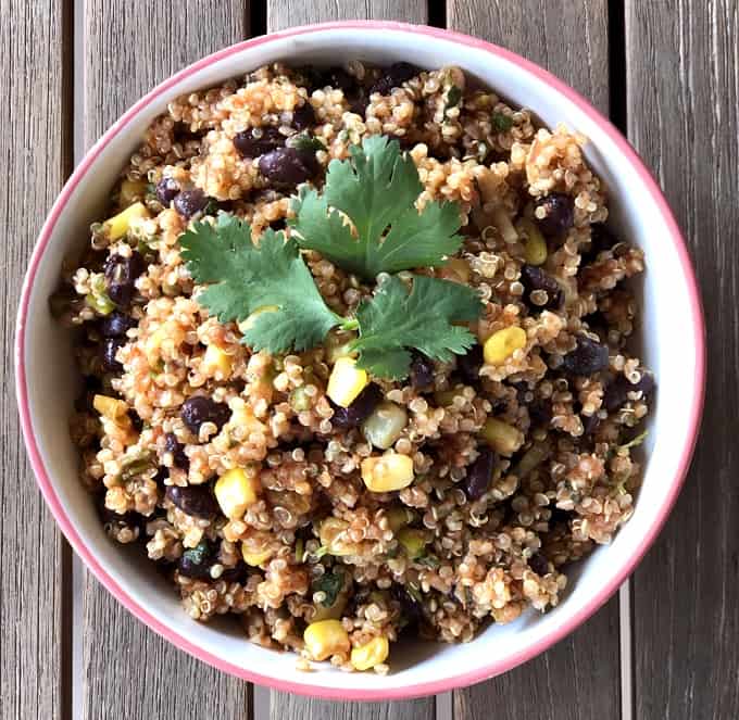 Quinoa salad with corn, black beans, salsa and garnished with fresh cilantro in bowl from above.