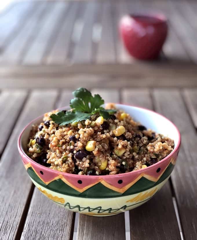 Quinoa with black beans and corn in decorative bowl topped with fresh cilantro.