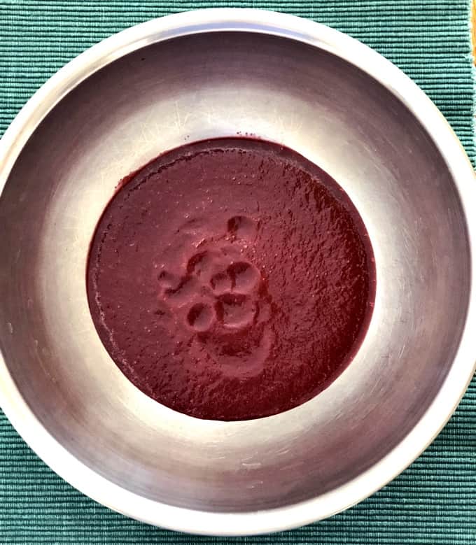 Beet puree in stainless steel bowl on green placemat.