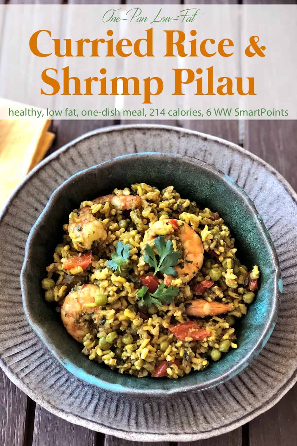 Curried rice shrimp pilau/pilaf in green ceramic dish on wooden table.