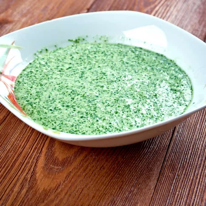 Spicy Peruvian Aji Verde Sauce in white bowl on wood table.