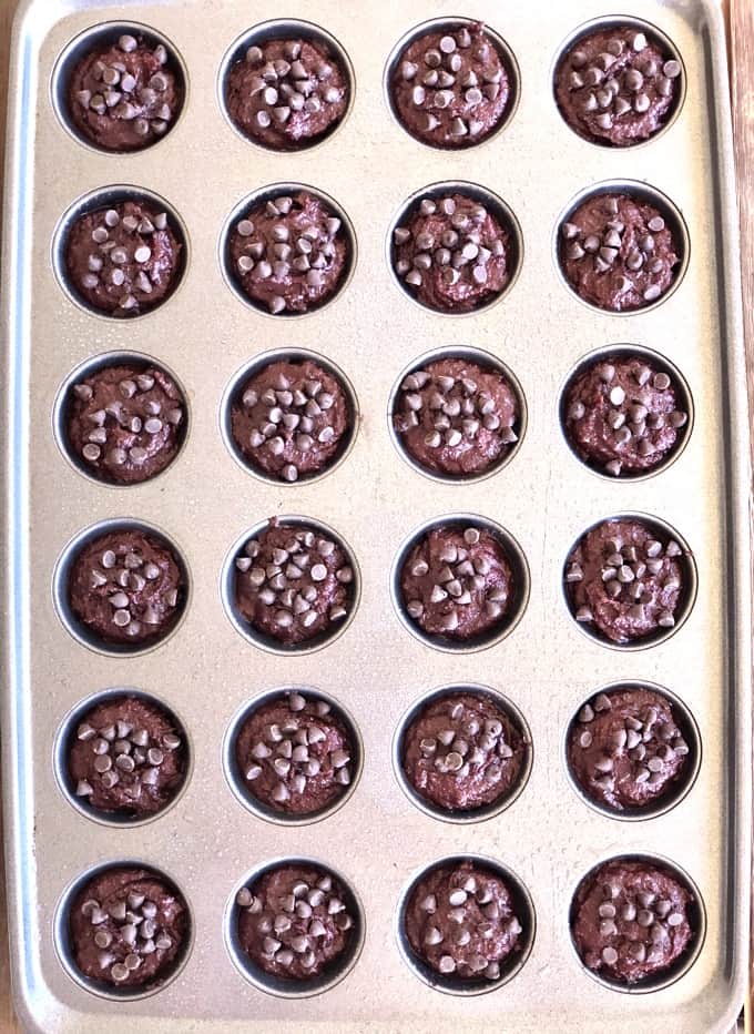 Unbaked mini beet brownies topped with chocolate chips in muffin tin.