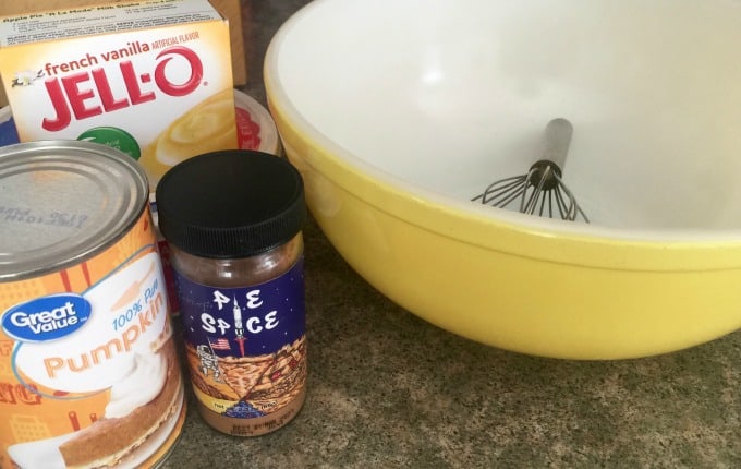 Pumpkin Fluff Ingredients - pudding mix, pumpkin, spices, cool whip, milk with yellow mixing bowl and whisk.