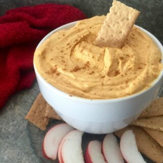 ramekin of pumpkin mousse fluff surrounded by sliced apples and graham crackers with red napkin in background