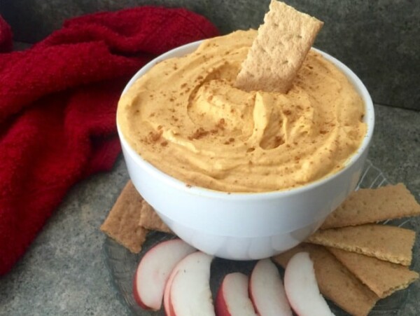 ramekin of pumpkin mousse fluff surrounded by sliced apples and graham crackers with red napkin in background