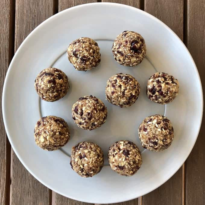 Cranberry date walnut energy bites on blue plate on wooden table.