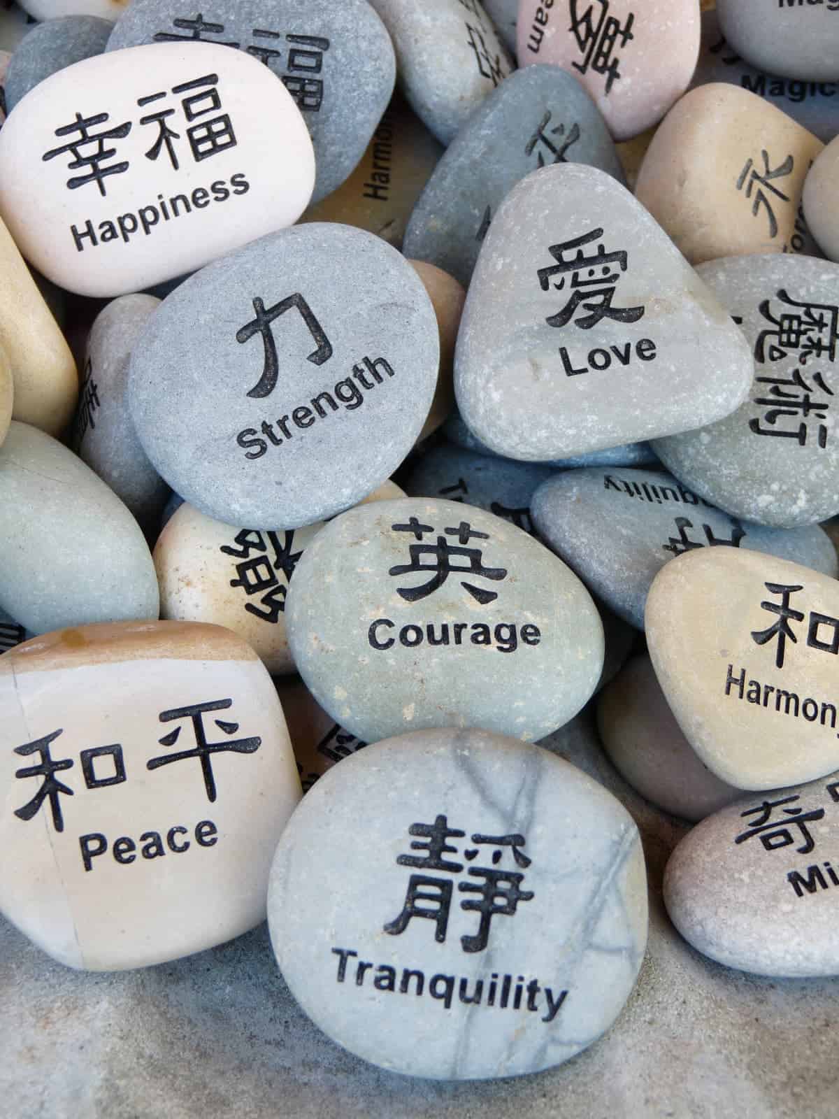 Inspirational words and Asian characters written on pile of colorful rocks.