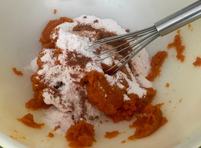 Mixing pumpkin puree, pudding mix, milk and spices with wire whisk in mixing bowl.