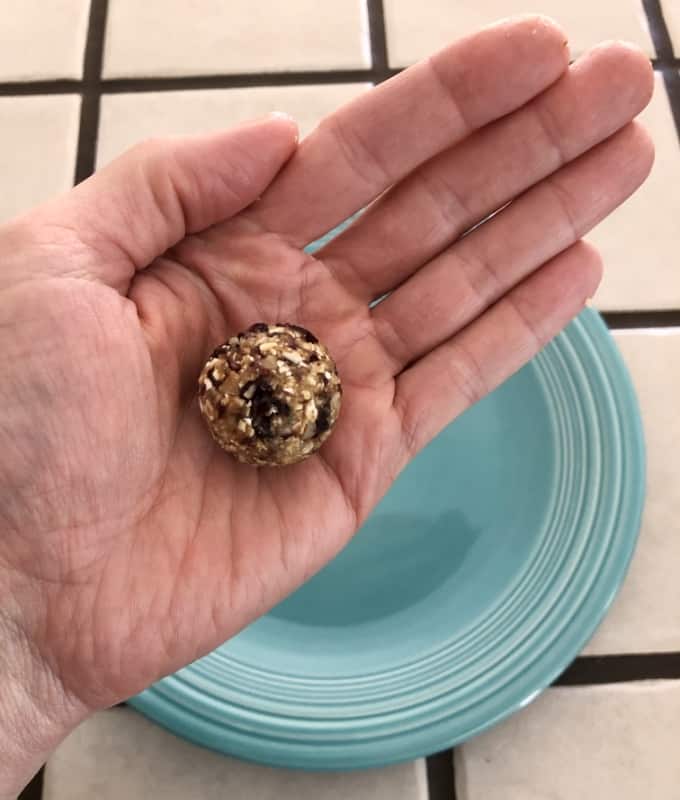 Rolling cranberry date nut energy bites into balls between palms.