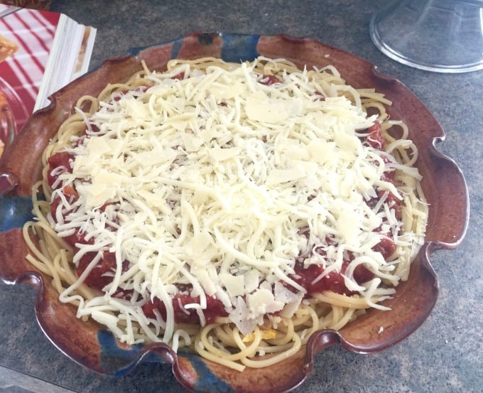 Spaghetti in ceramic pie plate with layers of ricotta cheese, meat sauce and shredded mozzarella.
