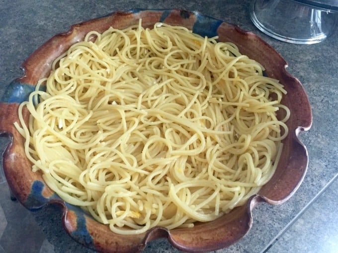 Pressing cooked spaghetti into ceramic pie plate.