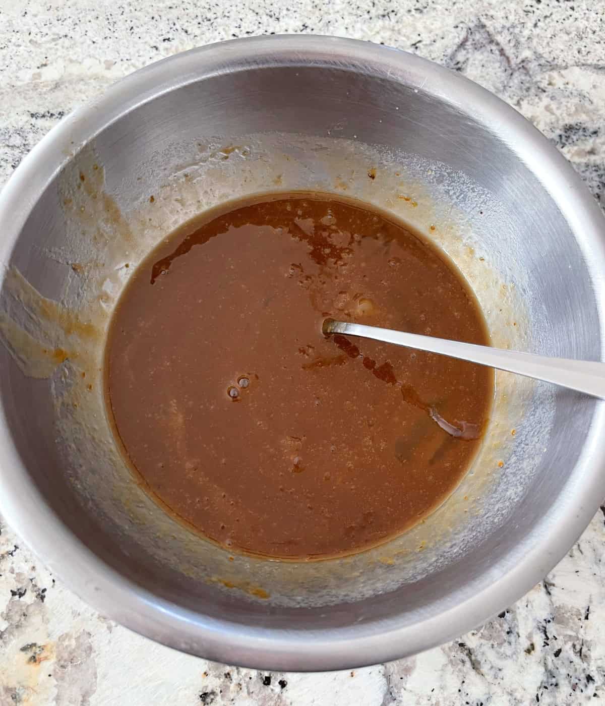 Mixing brown sugar, unsweetened applesauce, canola oil, egg and milk in mixing bowl with a spoon.