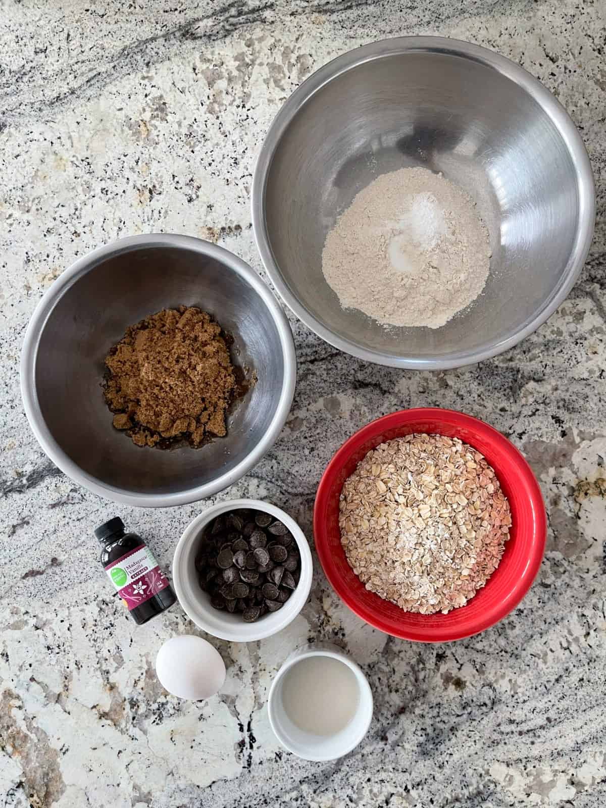 Ingredients including all-purpose flour, baking powder, salt, brown sugar, vanilla extract, chocolate chips, oats, milk and an egg.