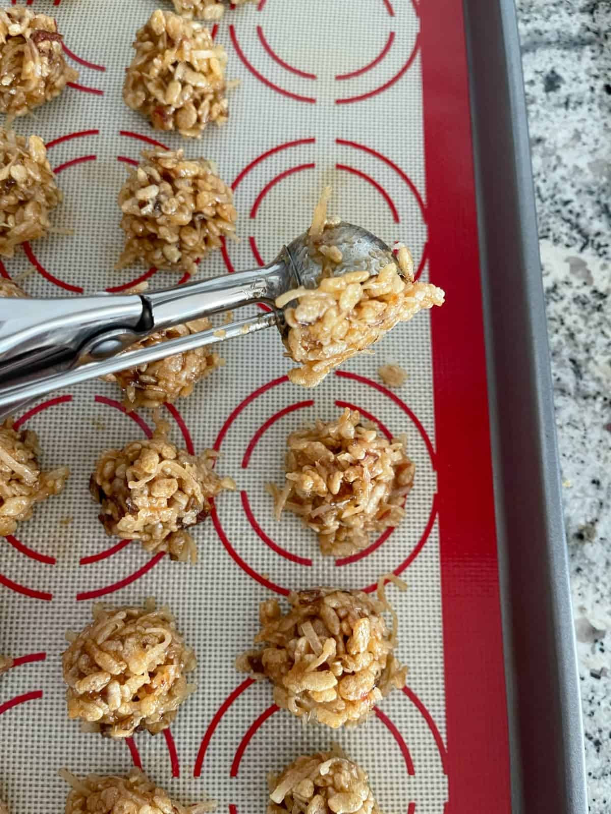 Using cookie scoop to shape Rice Krispies date balls.