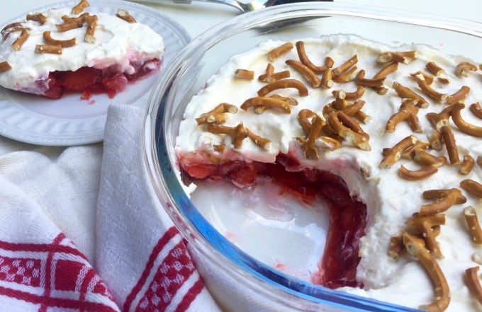 Layered Strawberry Pretzel Salad in pie dish next to small serving of salad on a small white plate.