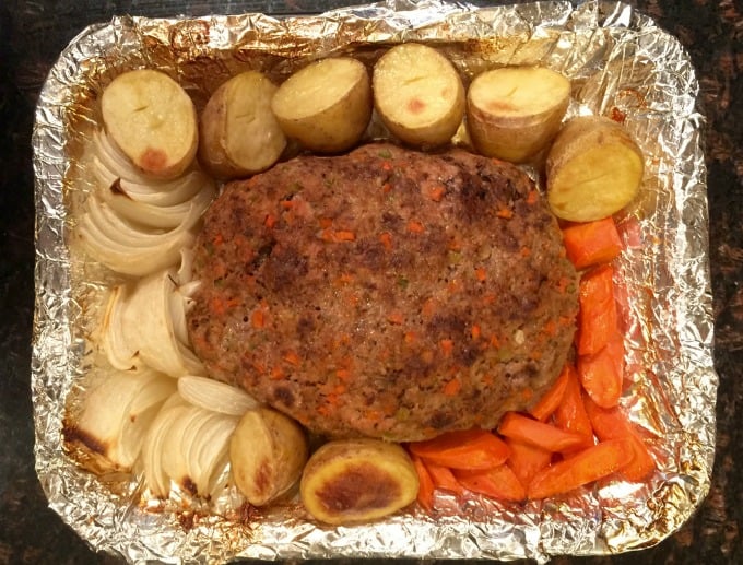  Foil-lined pan with meatloaf, potatoes carrots and onions.