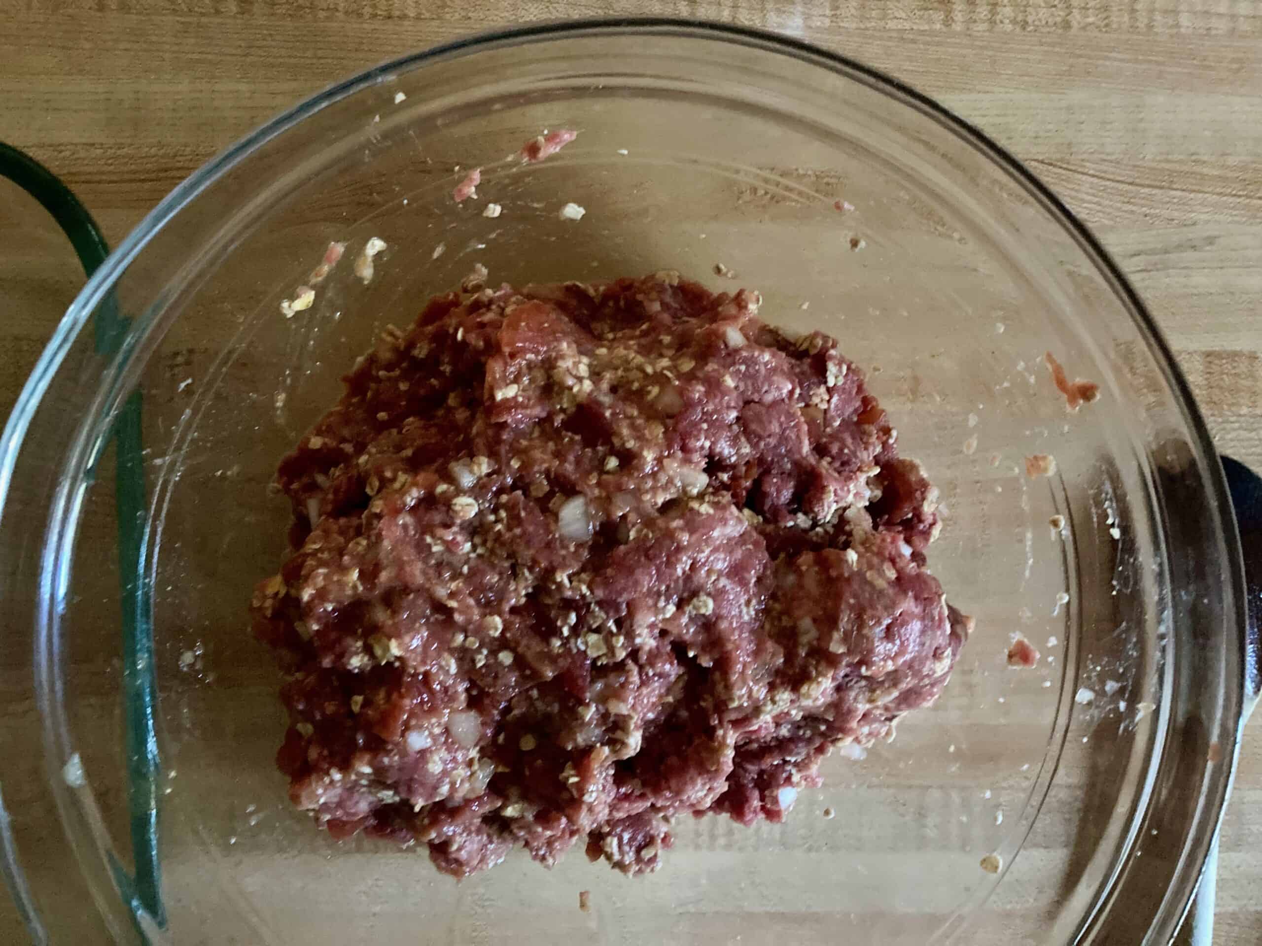 Glass mixing bowl with meatloaf ingredients blended together