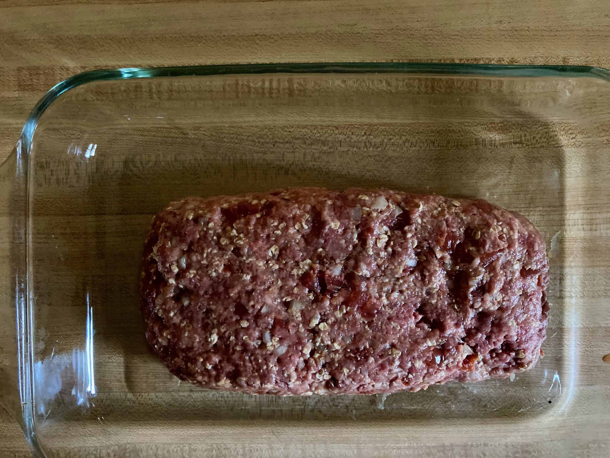 Raw meatloaf in a glass baking dish