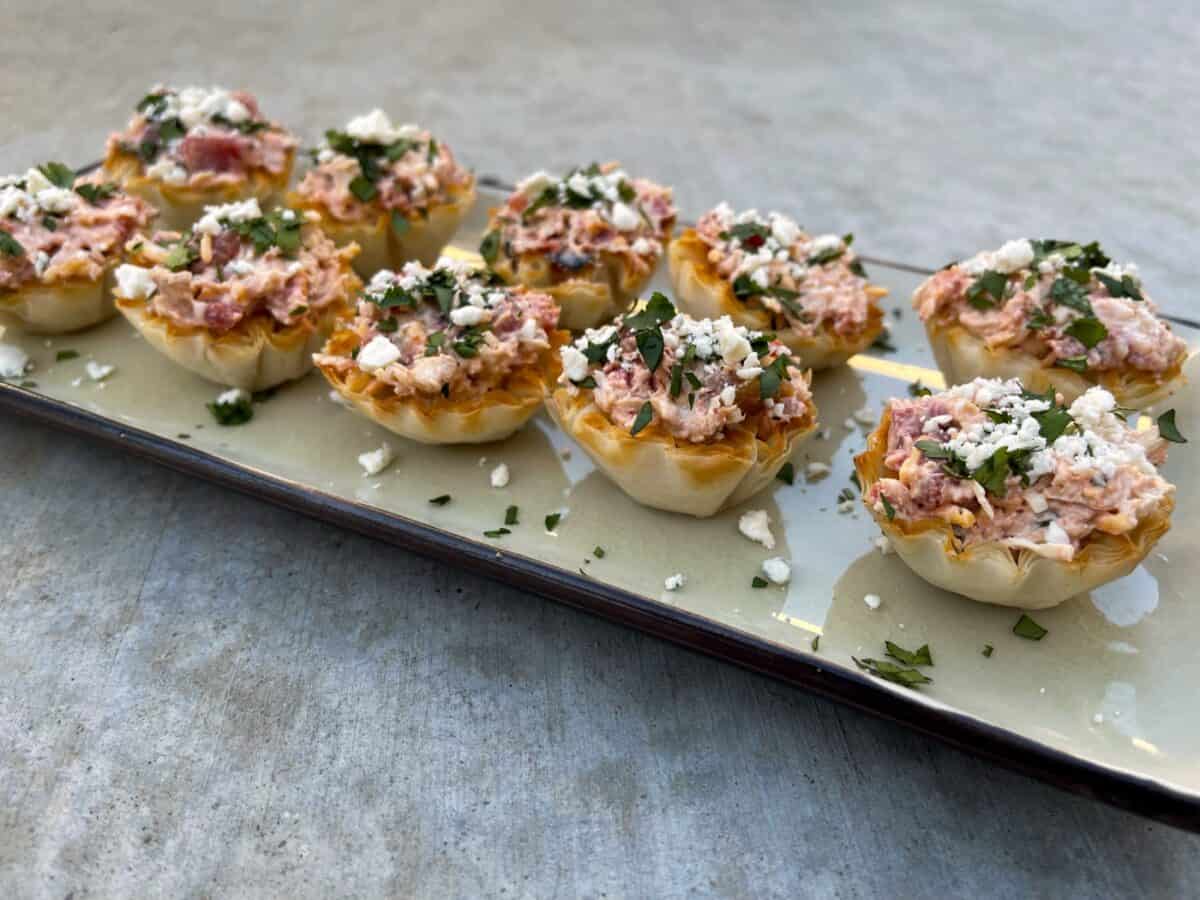 Mini Buffalo Chicken Bites topped with blue cheese crumbles and chopped cilantro on a serving plate.