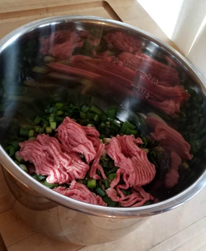 Ground turkey and chopped green onions in Instant Pot insert.