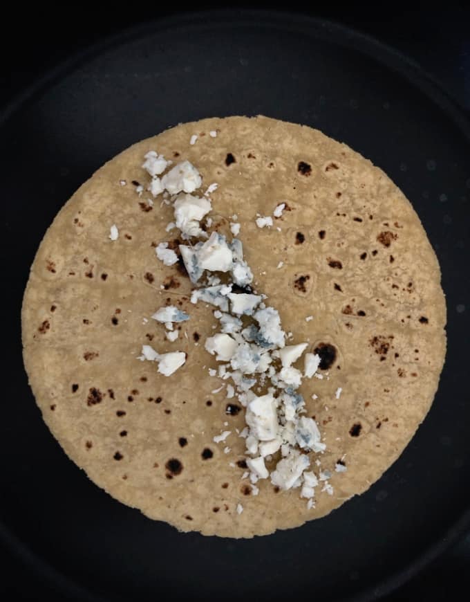 Tortilla with crumbled blue cheese in skillet