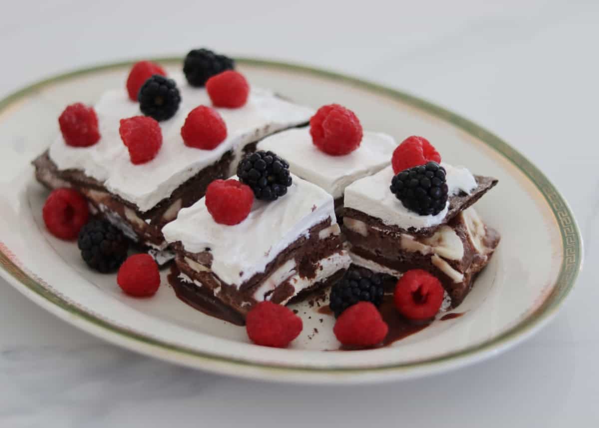 Chocolate fudge ice cream bar ice box cake dessert with fresh blackberries and raspberries on platter.