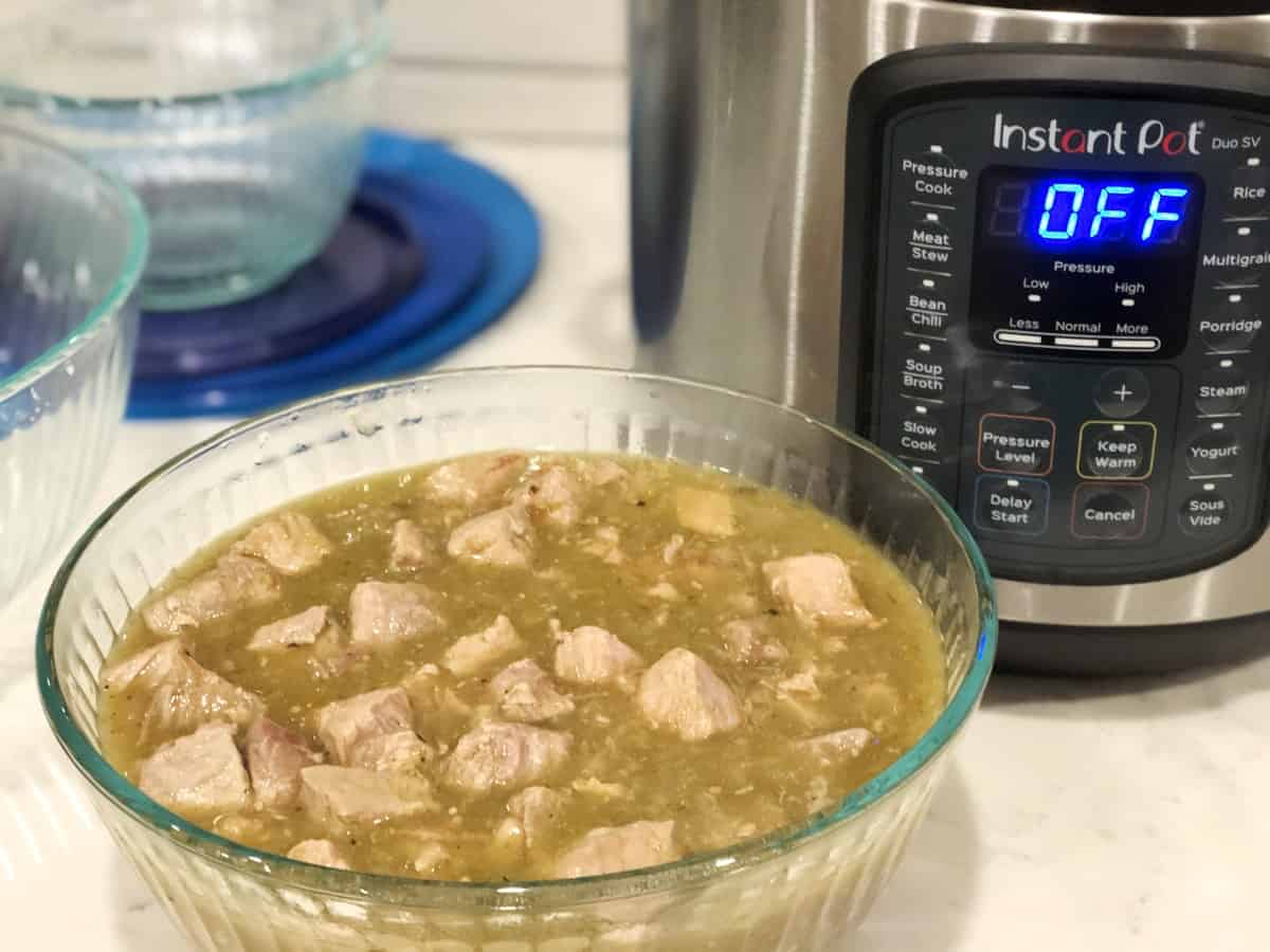 Fresh cooked green chili pork in glass bowl with InstantPot in background
