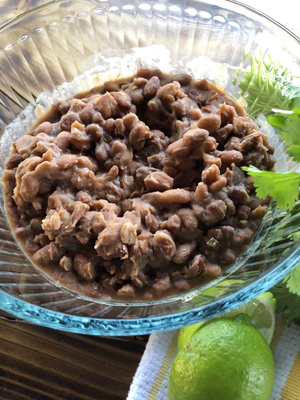 Cooked pinto beans in small glass bowl with fresh limes