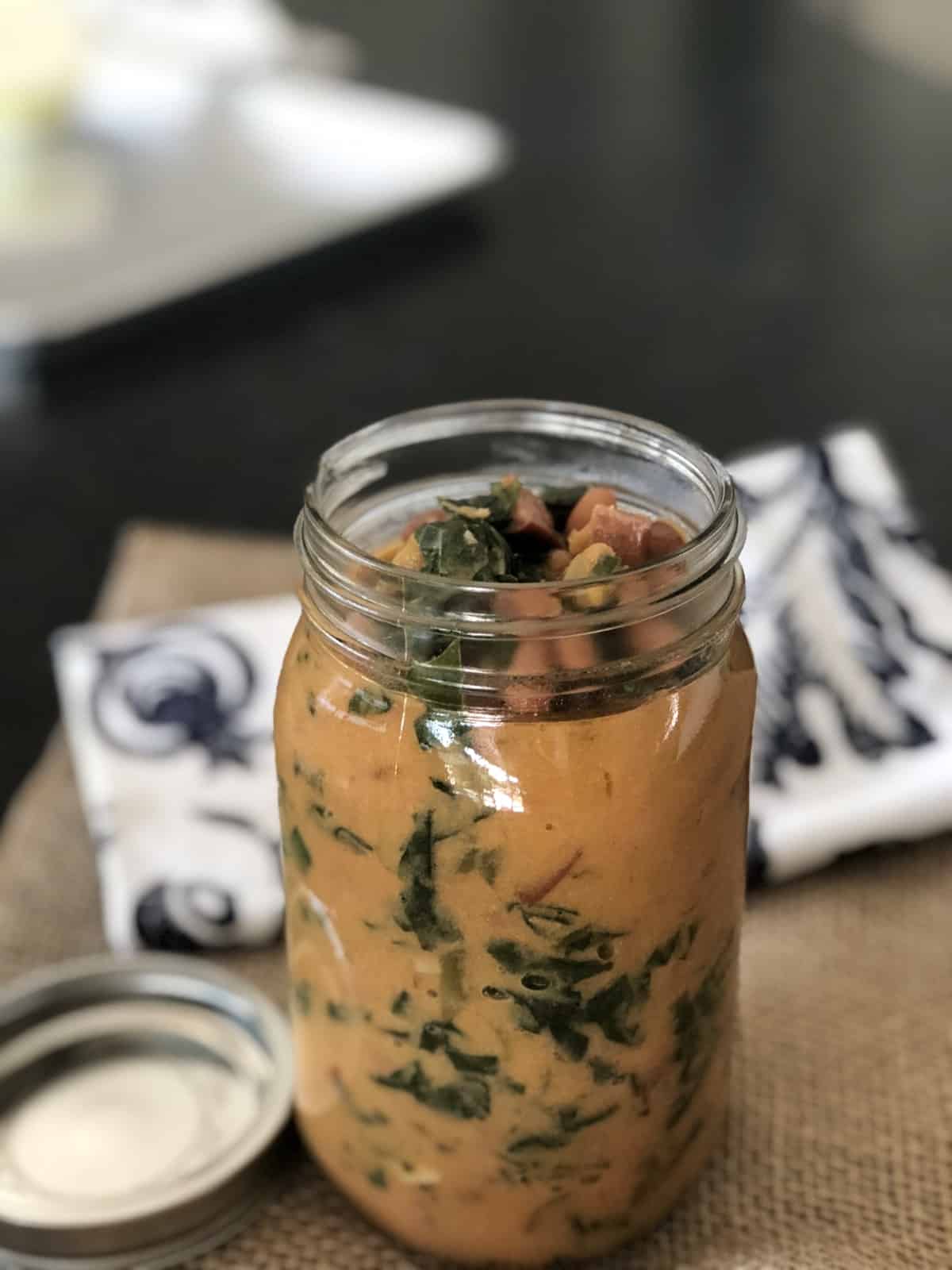 Mason jar filled with Southern Bean Soup on burlap mat on kitchen counter.
