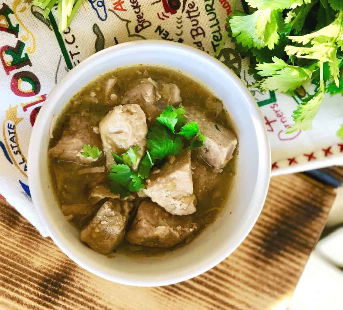 Instant Pot pork chili verde in white bowl with cilantro from above.