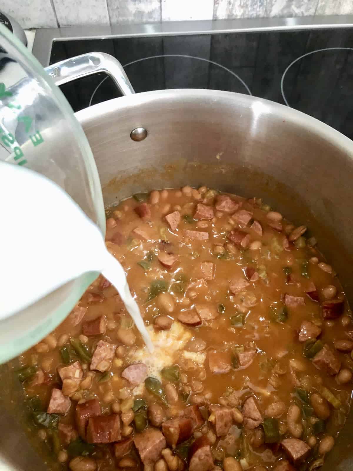 Adding milk to soup stock pot.