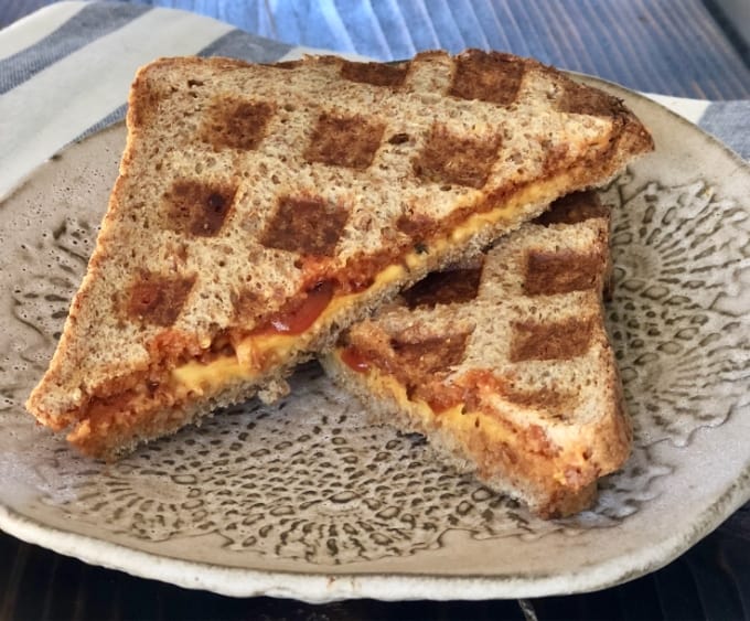 Waffled tomato soup grilled cheese sandwich on ceramic plate.