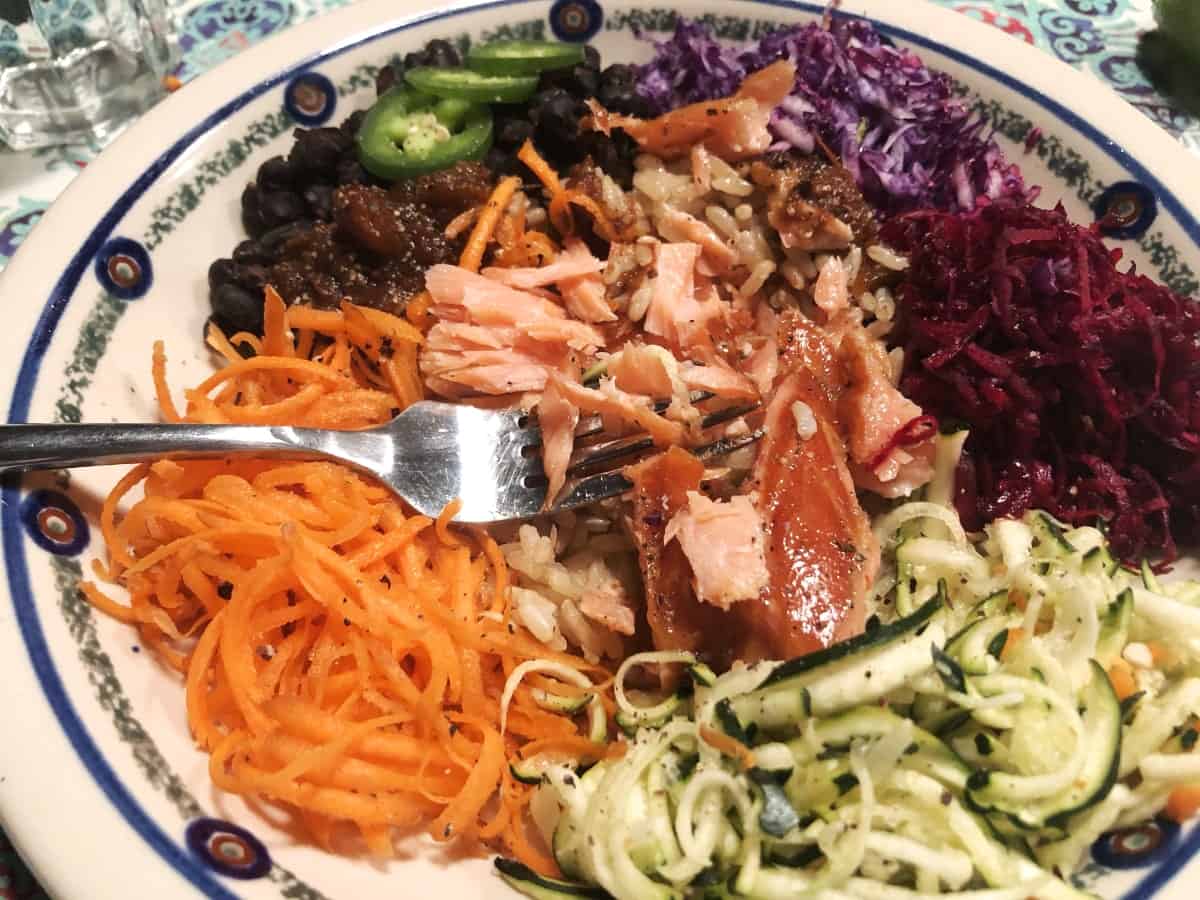 Salmon bowl with brown rice, black beans, shredded carrots, zucchini, beets and cabbage.