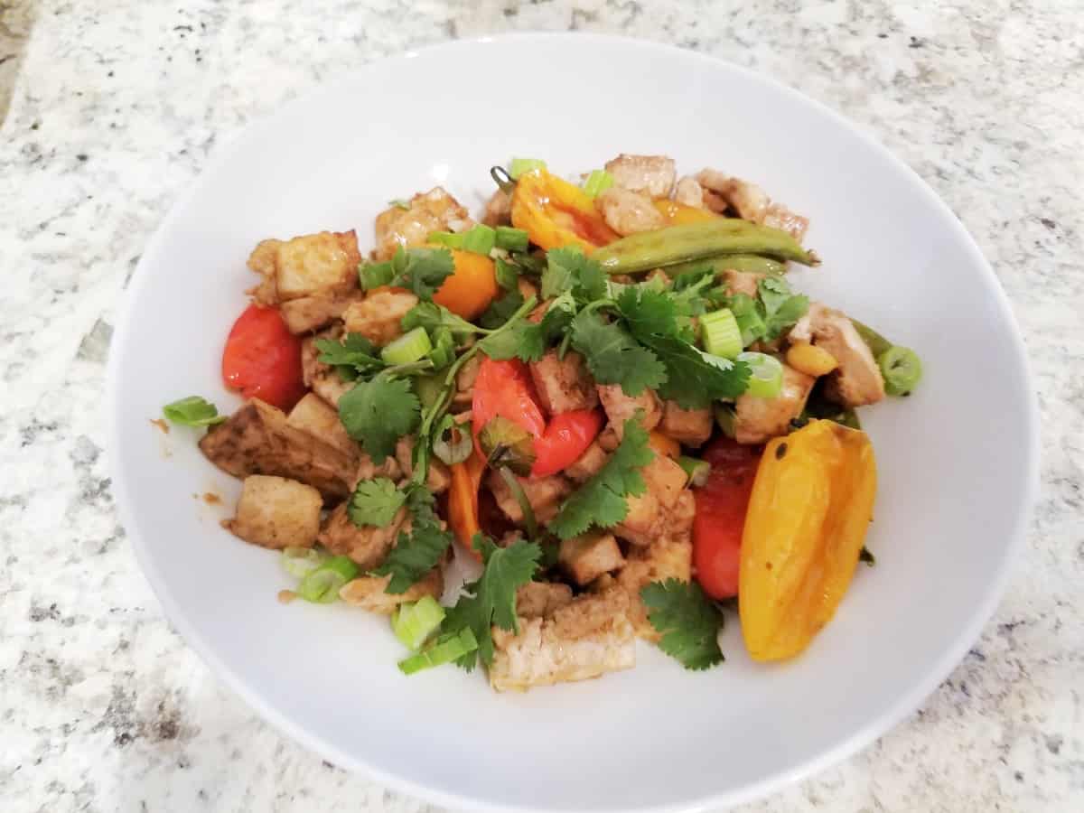 Ginger sesame baked tofu with peppers and snap peas on white plate