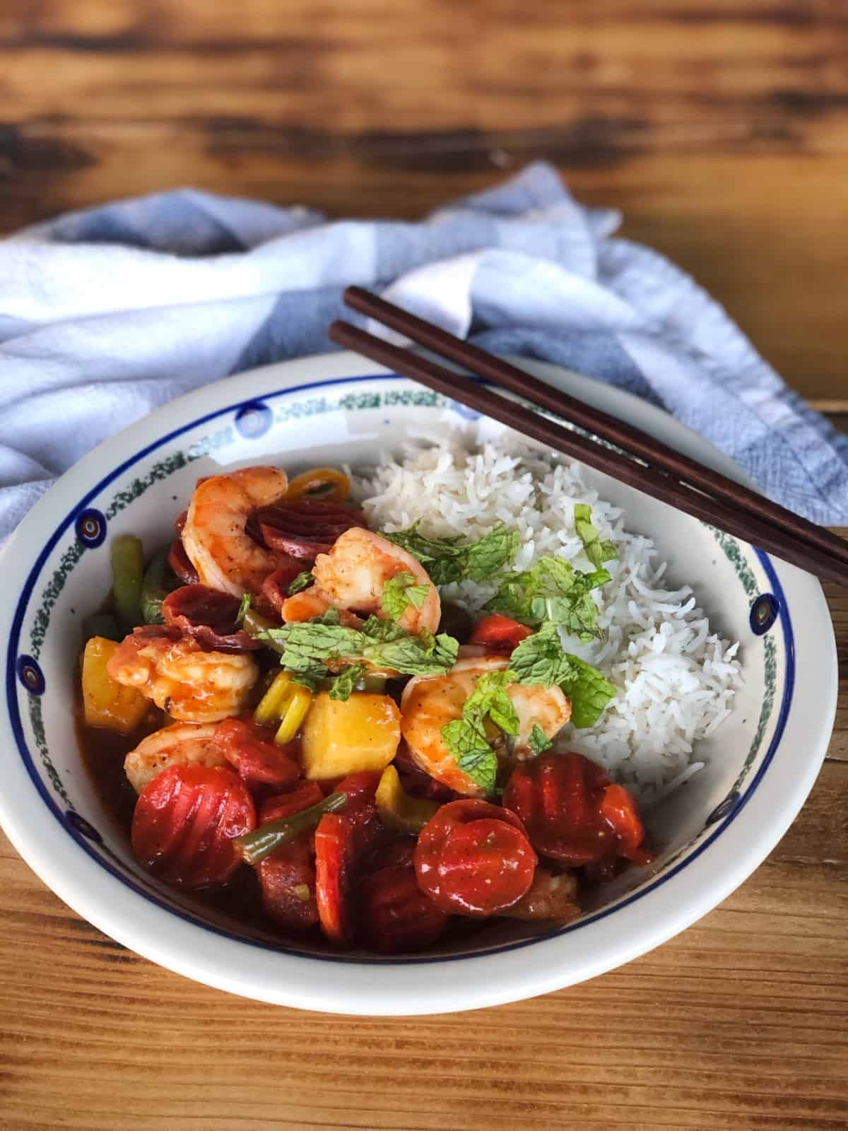 Caribbean Shrimp with Pineapple and Mixed Vegetables in bowl with white rice and chopsticks on wood table.