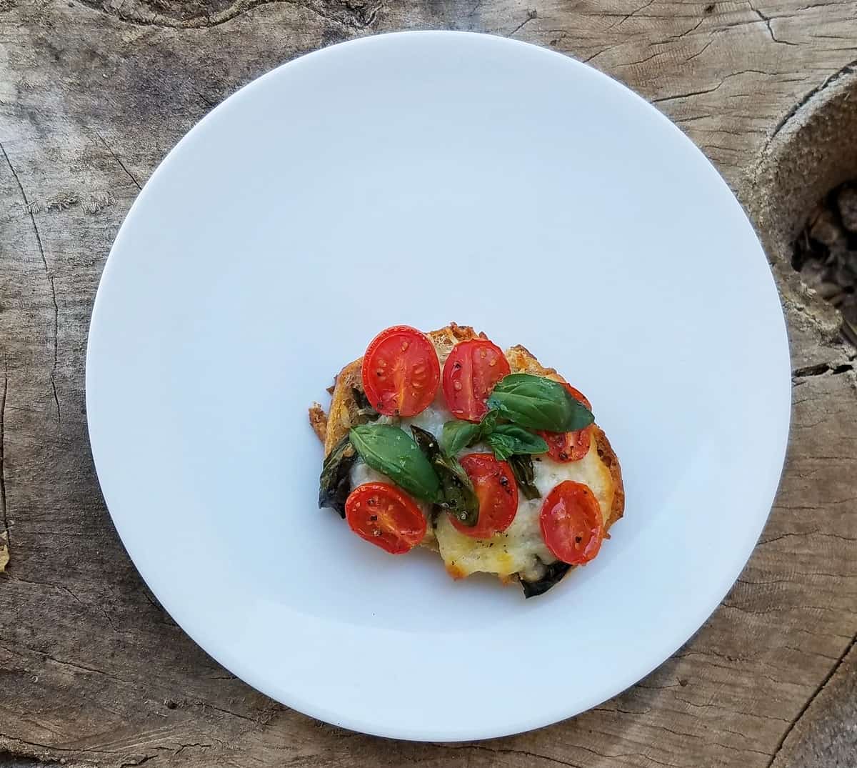 Toasted caprese sandwich on white plate from above.
