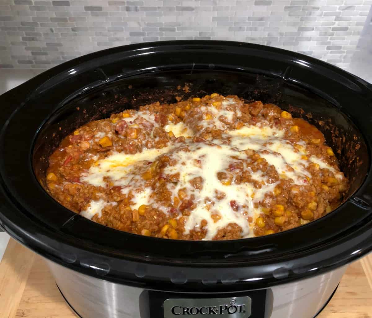 Cooked tamale pie with melted cheese in crock pot.
