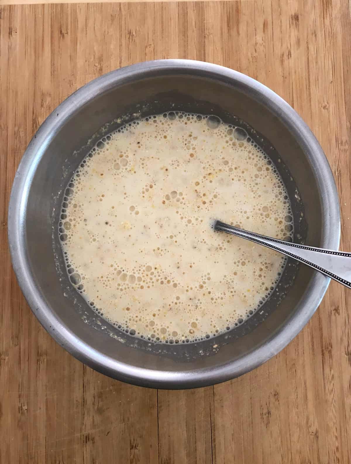 Mixing together cornmeal, milk and egg in stainless mixing bowl.
