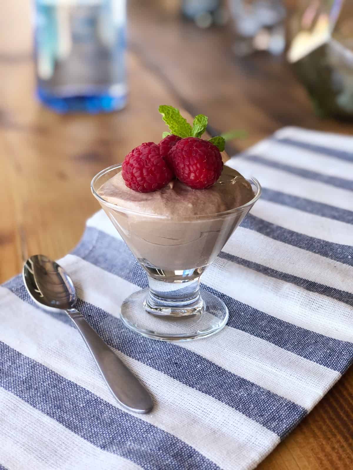 Stemmed dessert glass filled with Nutella mousse and garnished with fresh raspberries and mint.