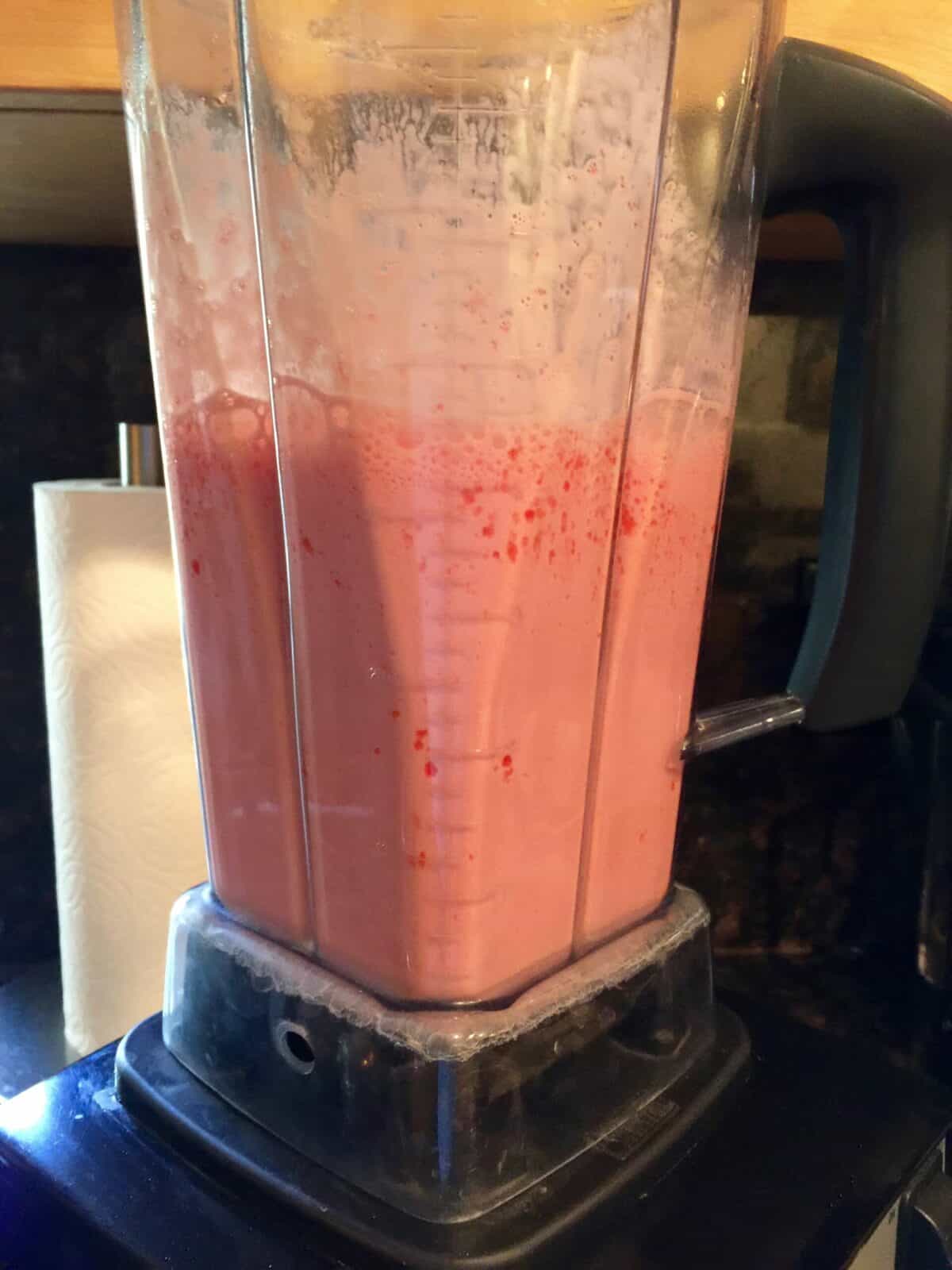 Mixing strawberry jello yogurt fluff in blender.