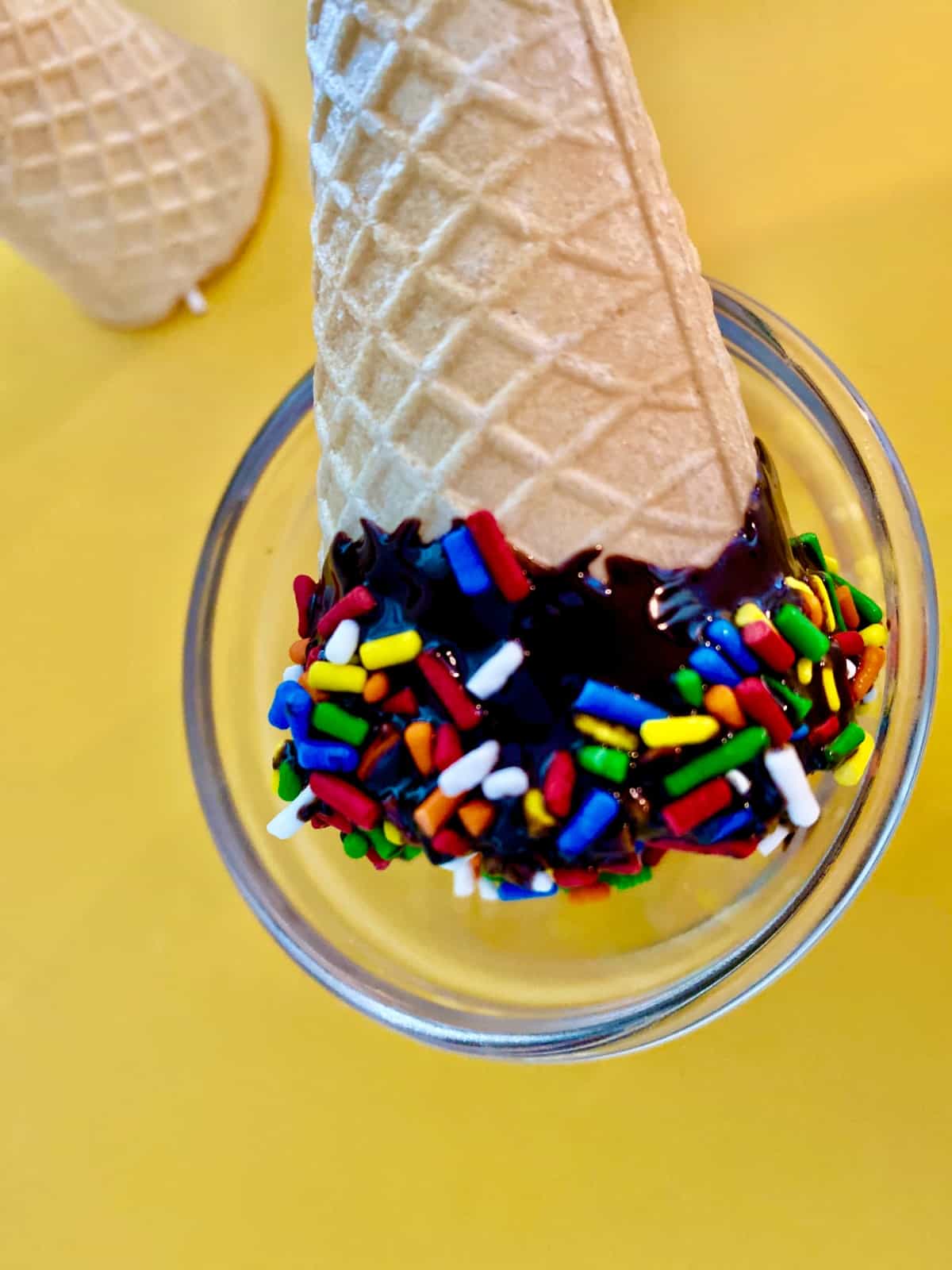 Ice cream cone with melted chocolate and sprinkles.