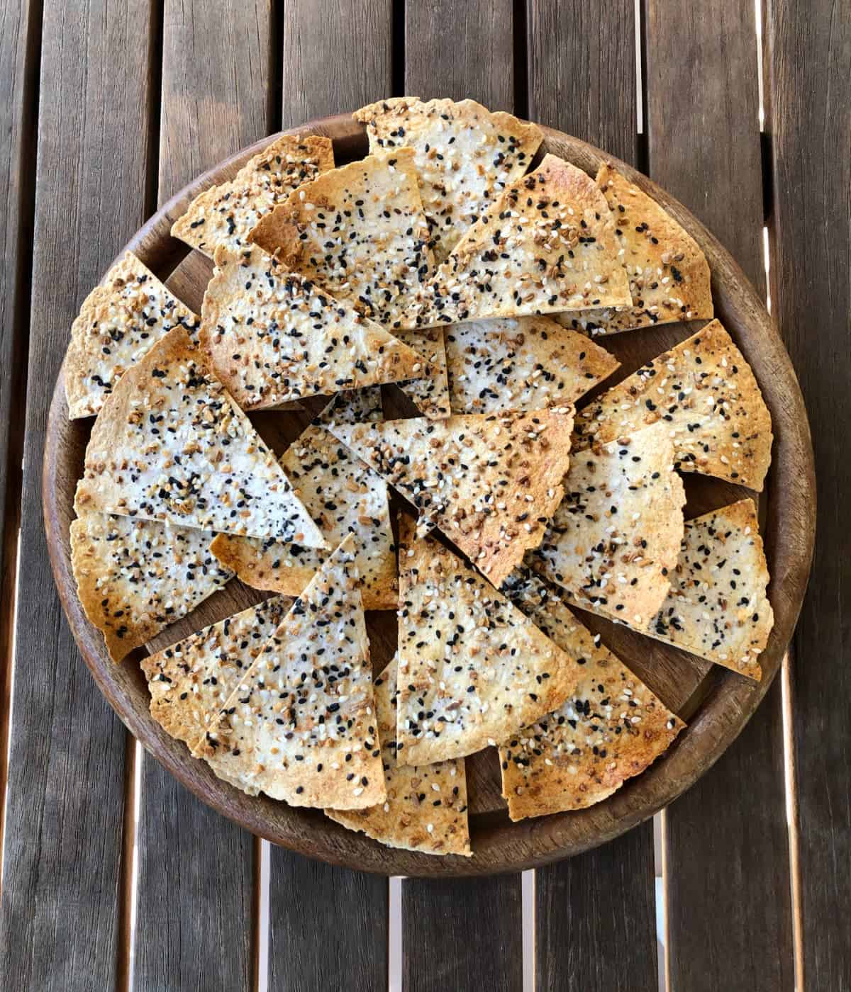 Homemade everything but the bagel seasoning snack chips on wood table.