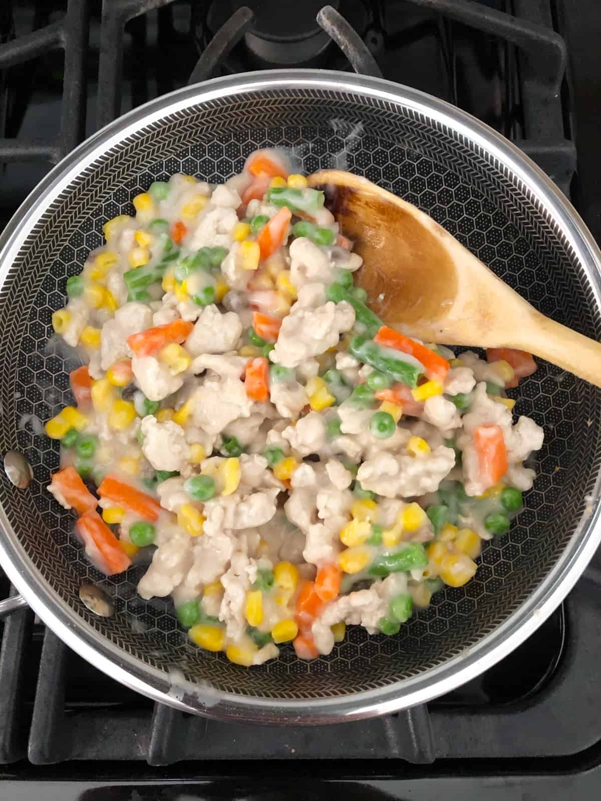 Cooking ground turkey, mixed vegetables in cream of mushroom soup in skillet.